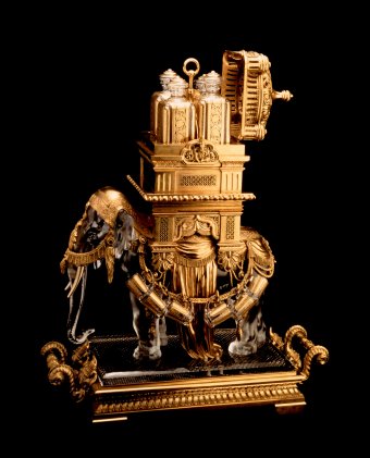 Fig. 3: Liqueur cabinet in the shape of an elephant with a howdah, pressed, etched, cut, gilded; gilded bronze. Made for the Baccarat display at the 1878 world's fair in Paris. H. 65 cm, L. 58 cm. Four carafes fit inside the palanquin, and 12 mugs hang from the bronze harness. The Crillon Palace, Paris.